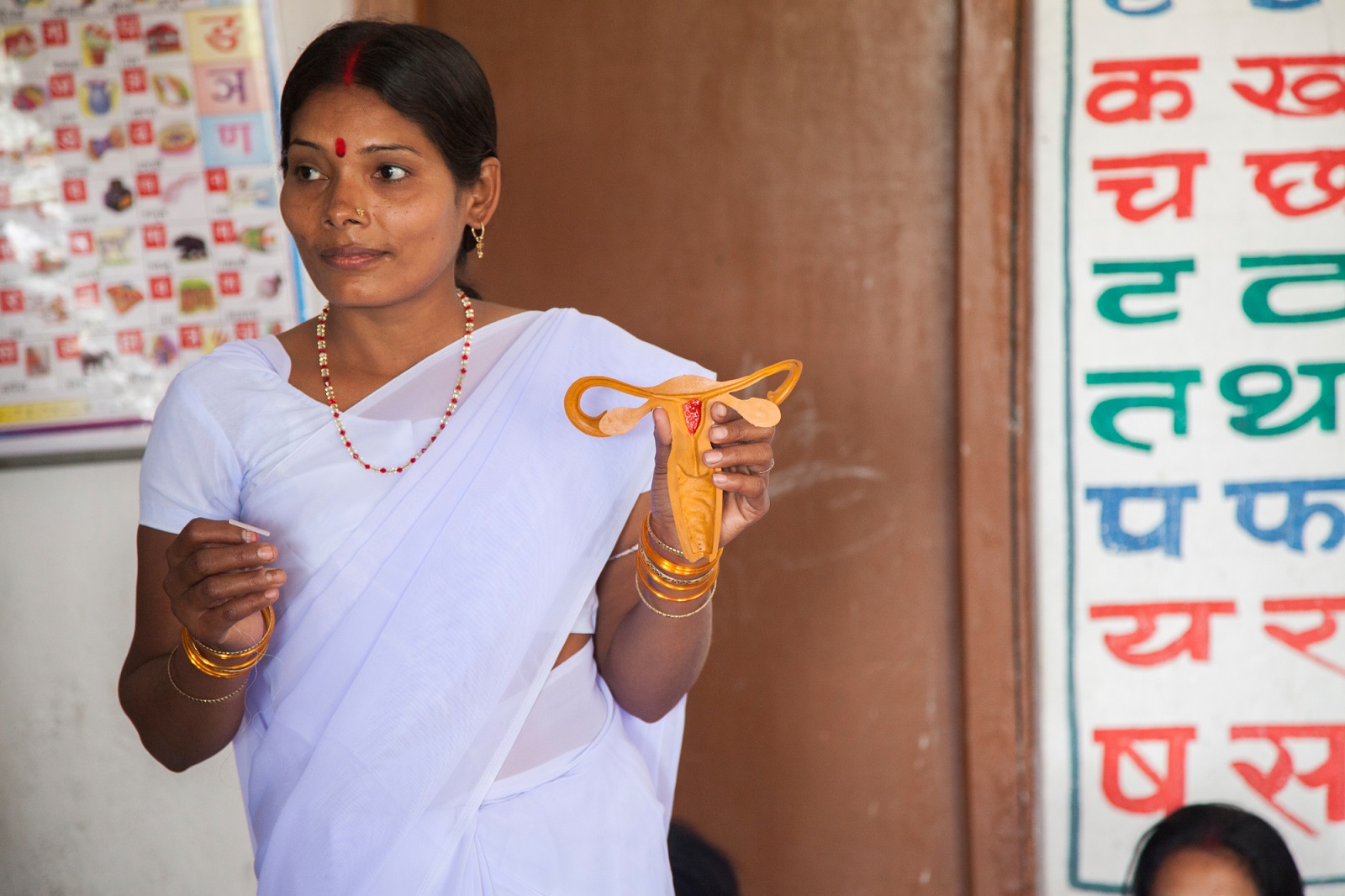 Auxilliary Nurse & Midwife Supriya Kumari (in plain white sari) uses a demonstartion Copper T and a Uterus model during a Sub-centre meeting of Frontline Health Workers at an Anganwadi Centre in Shahideeh village in Navhatta East block, Saharsa district, Bihar, India.