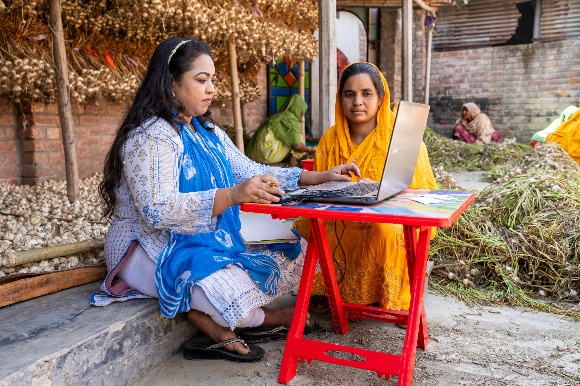 Jhuma Khatun (30), a SATHI Network agent, helps Morzina Begum (40) to open a bank account in Rajshahi, Bangladesh, on April 2, 2024. 