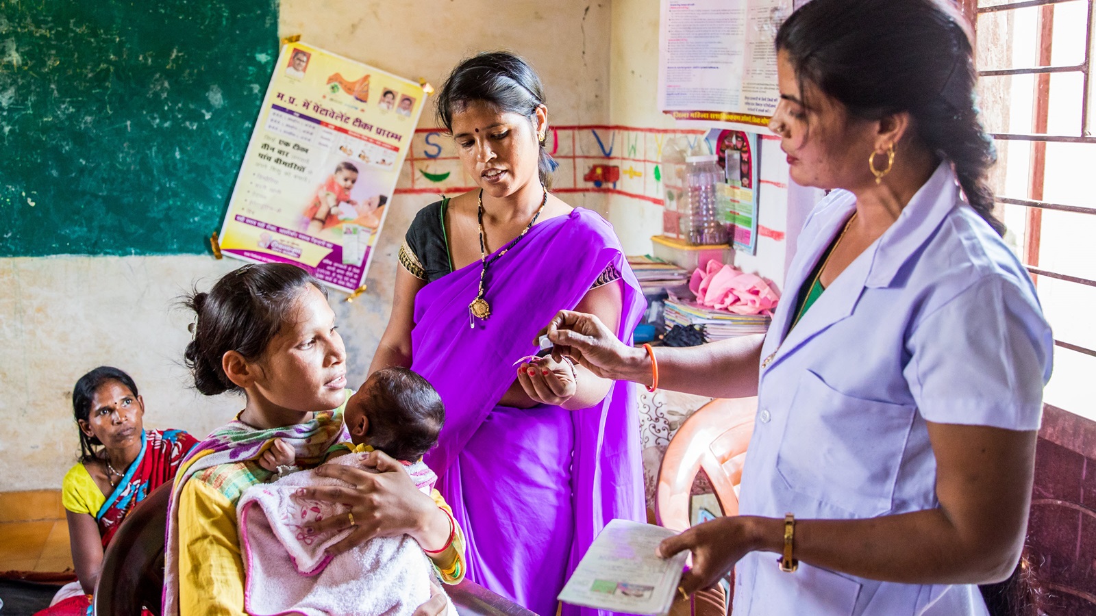 An Auxiliary Nurse Midwife (ANM), explains the post care of the vaccinations given to a mother and child at an Anganwadi Centre (AWC) in Bhopal, Madhya Pradesh, India