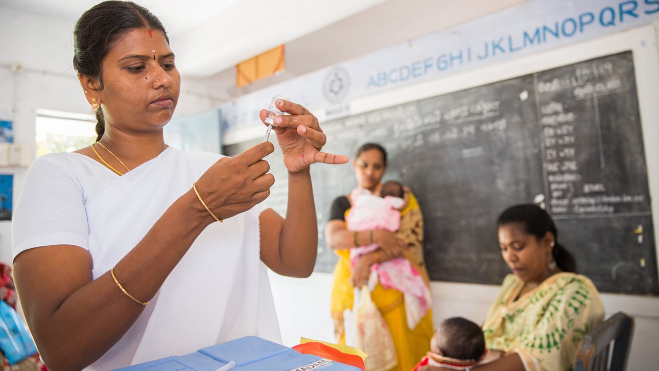 A health worker prepares to vaccinate a young child at a health center in Vellore, India