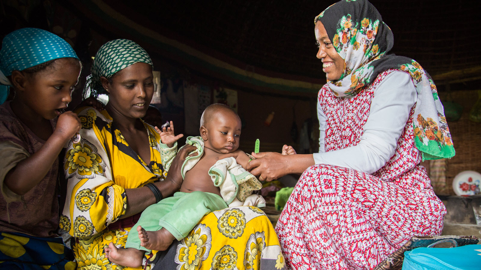 A health extension worker in Ethiopia takes an infant’s temperature.