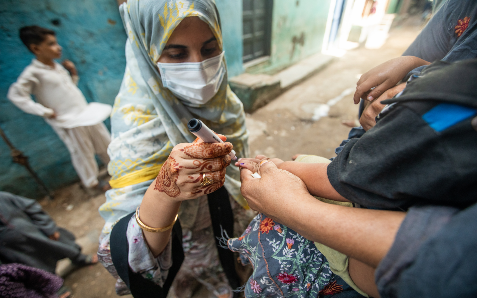 A polio vaccinator marks a young child in Karachi, Pakistan. 