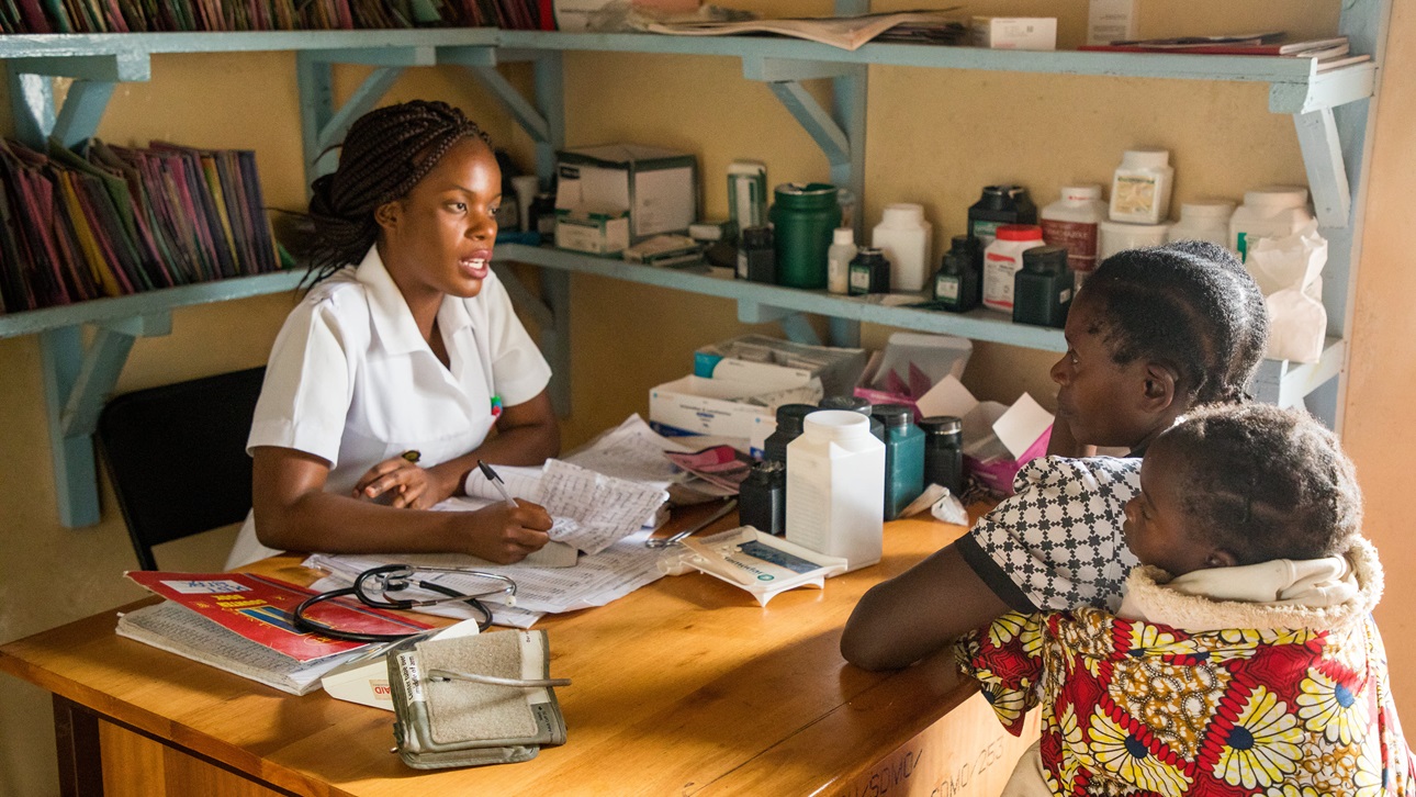 A health care worker explains malaria treatment options at a rural health center in Zambia.