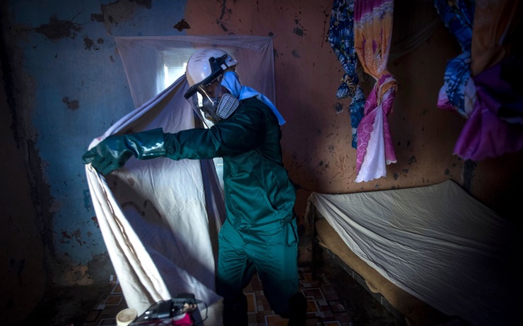 Bismark Owusu, a worker of Anglogold Ashanti Malaria Ltd, covers furniture before spraying the walls of a house with insecticide against mosquitos in Adansi Domeabra, Ghana, in May 2018.  Insecticide resistance has become a huge problem, threatening an uptick in malaria cases in both rural and urban areas. 