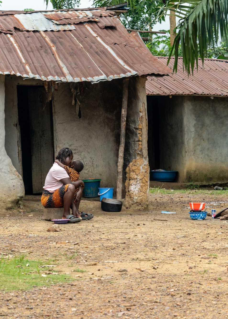 Tina Flomo sits with her son, Joseph in the yard of their home in Bong County, Liberia, on July 30, 2025.