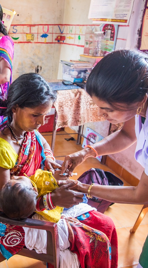Bimla Sahu, an ASHA (accredited social health activist) worker, weighs a child while Gayatri Ahirwar, an ANM (auxiliary nurse midwife), administers routine vaccinations in Bhopal, Madhya Pradesh, India. 