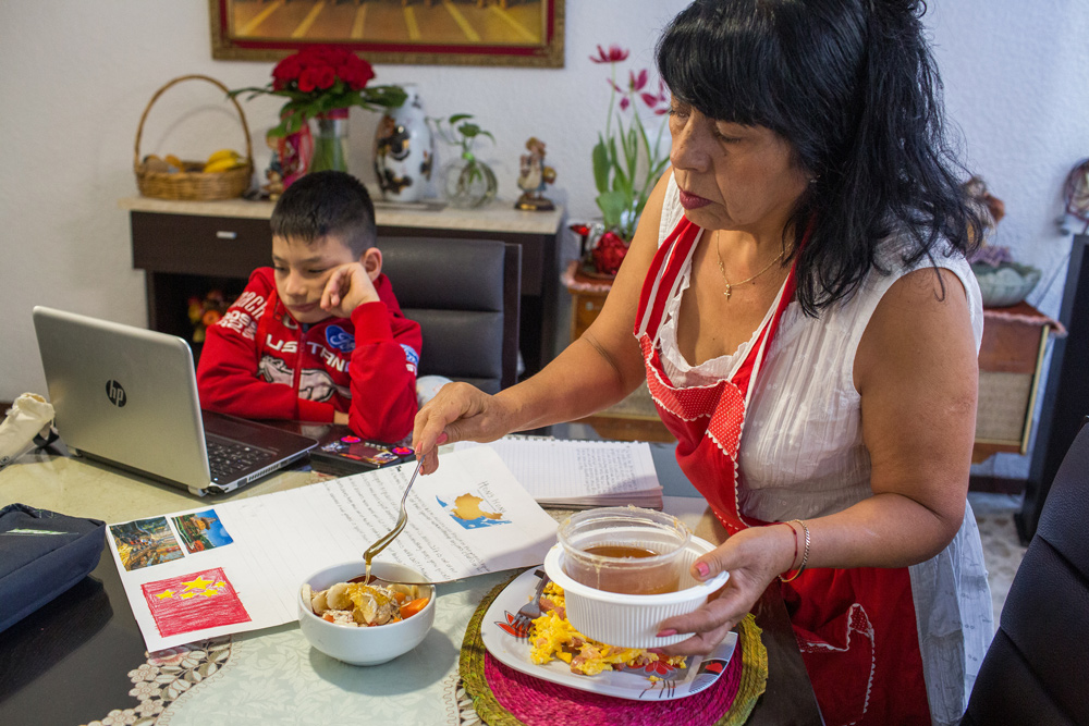 A woman serves breakfast to her grandson in her home in Mexico City, Mexico.