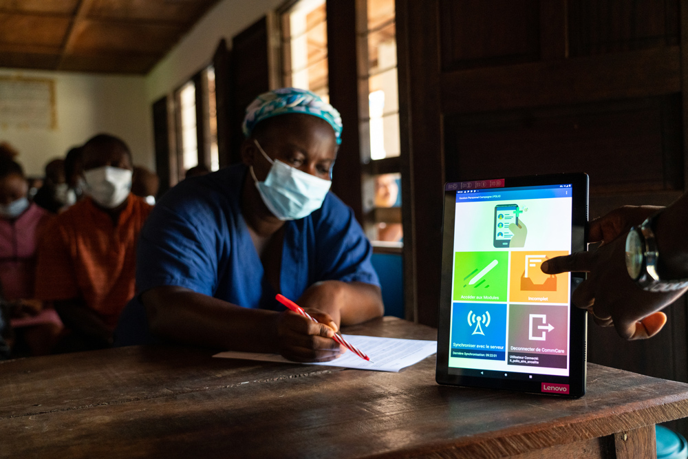 A health care worker signs up for government digital payments by mobile phone in Mangobo, DRC.