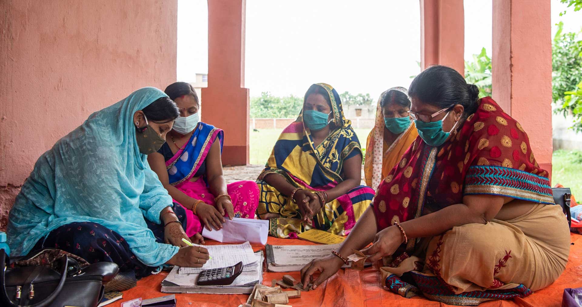 Сони Шарма (в синем), мобилизатор сообщества и «диди» или член группы самопомощи, организованной Дживикой, записывает денежные депозиты во время встречи ГСП в Гурмии, Бихар, Индия. (28 августа 2021 г.)