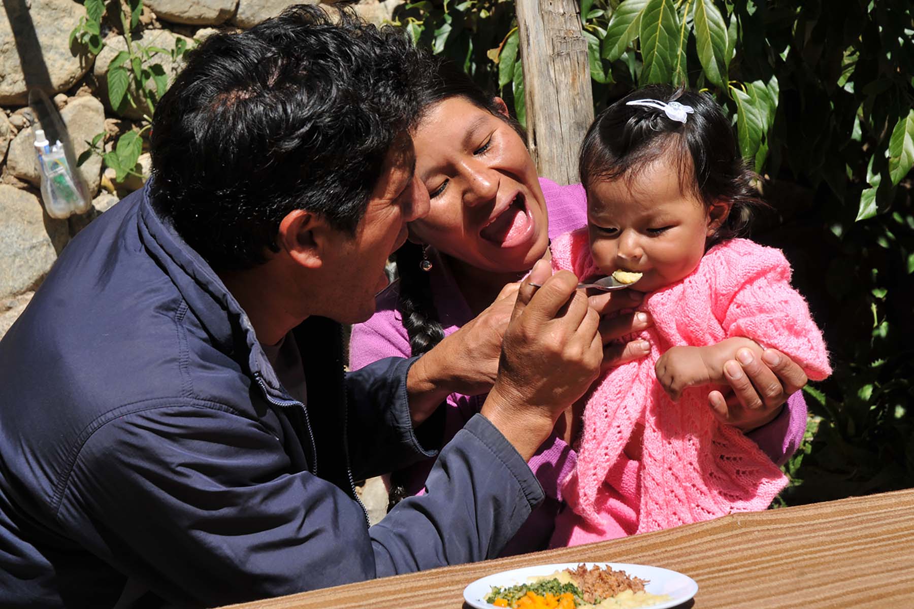 Picture of a father and mother feeding their child in one of Peru’s nutrition projects.