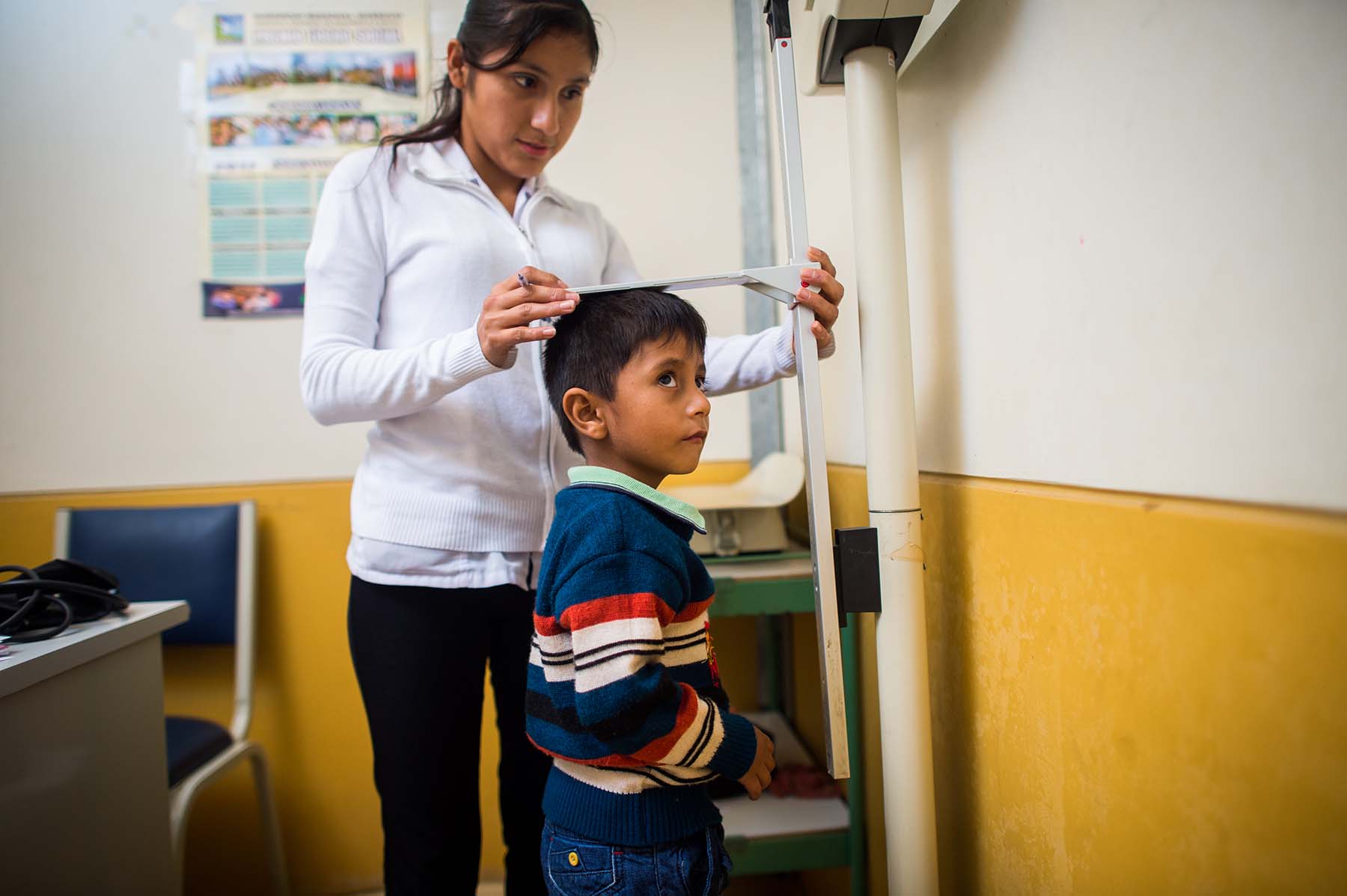 Picture of a nurse measures the height of a boy at a health clinic during a regular checkup. (Acomayo, Peru)